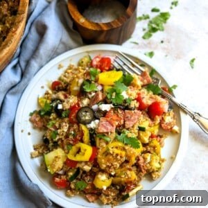 Italian Quinoa Salad on a white plate with a silver fork, close up.