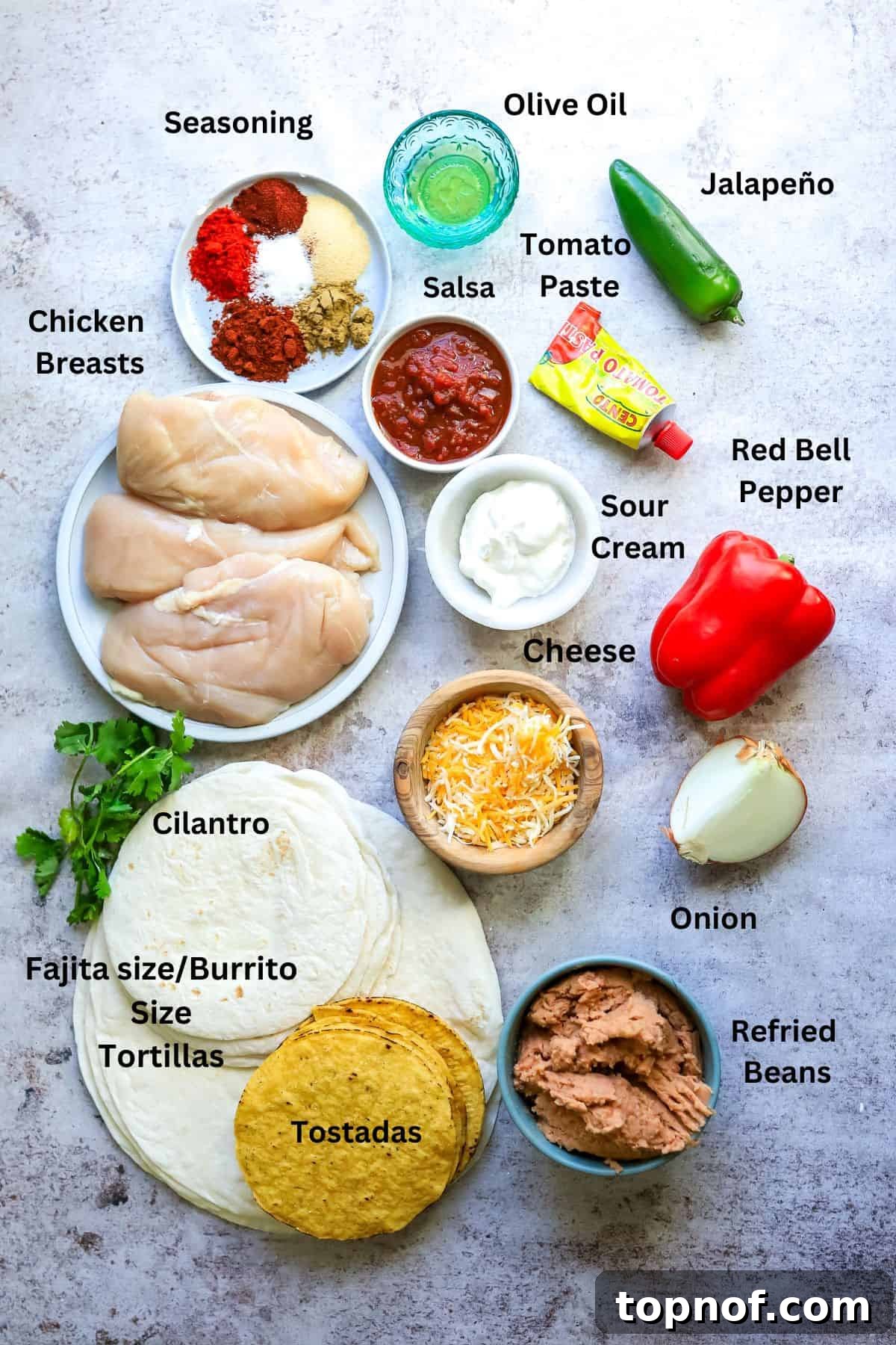 Ultimate Crispy Chicken Wrap 3 A vibrant display of fresh ingredients for chicken crunch wraps including chicken breasts, chopped bell peppers, onions, salsa, spices, tortillas, and refried beans in small bowls.