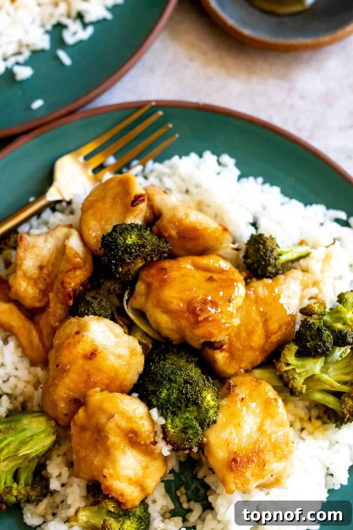 One-Pan Honey Butter Glazed Chicken 5 Green plate with rice and chicken and broccoli. Gold fork in the chicken. up close.