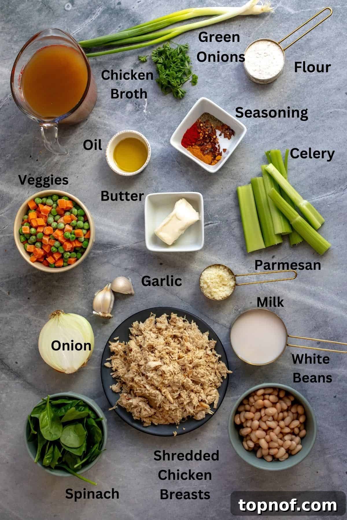 Velvety Chicken & Garden Vegetable Soup 3 Small bowls and plates display fresh ingredients including diced yellow onion, chopped celery, minced garlic, spices, butter, flour, and shredded chicken, ready to be prepared for the soup.