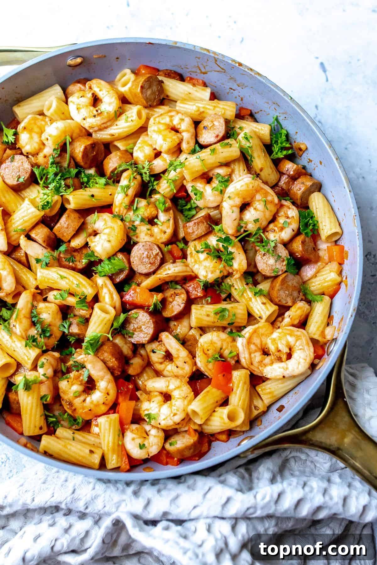 Cajun Kick Shrimp and Sausage Pasta 2 A beautifully presented close-up of creamy Cajun shrimp and sausage pasta in a rustic grey skillet, garnished with fresh parsley, highlighting the rich sauce and perfectly cooked ingredients.