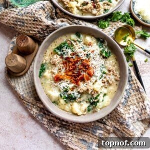 Grey pottery bowls filled with creamy soup and crispy bacon on top. Garnished with parsley and a gold spoon.