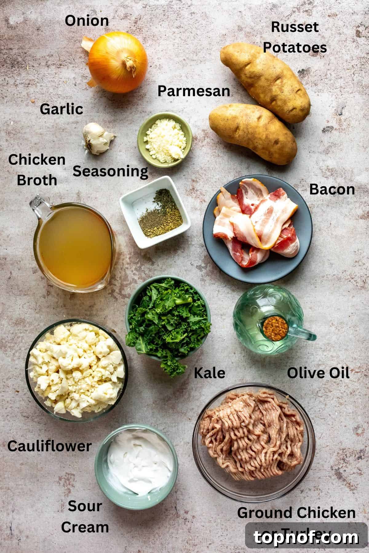 Slimmed-Down Slow Cooker Zuppa Toscana 3 Assortment of fresh ingredients laid out on a grey counter, including bowls of broth, diced vegetables, and raw ground meat, ready for soup preparation.