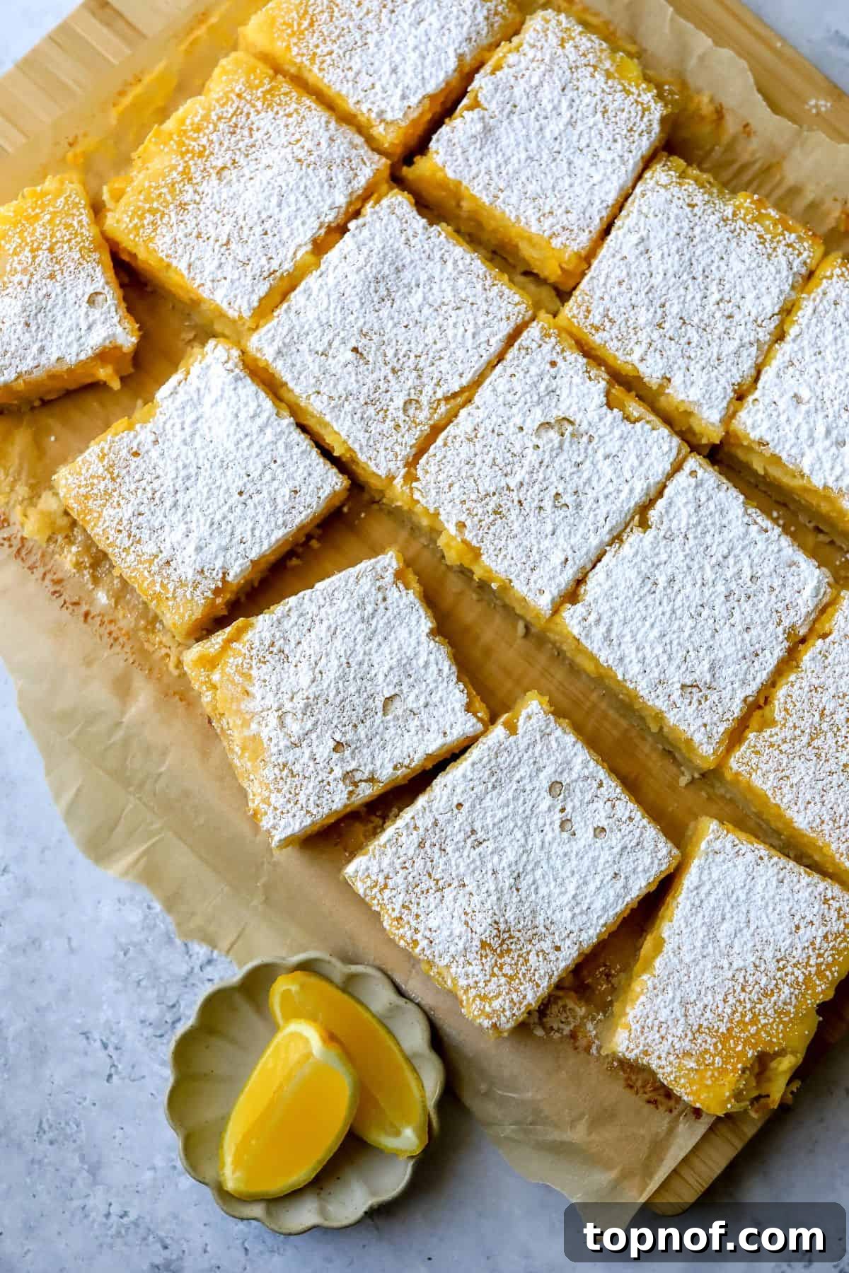 Bright and tangy Lemon Cookie Bars on a rustic wooden cutting board, garnished with fresh lemon slices.