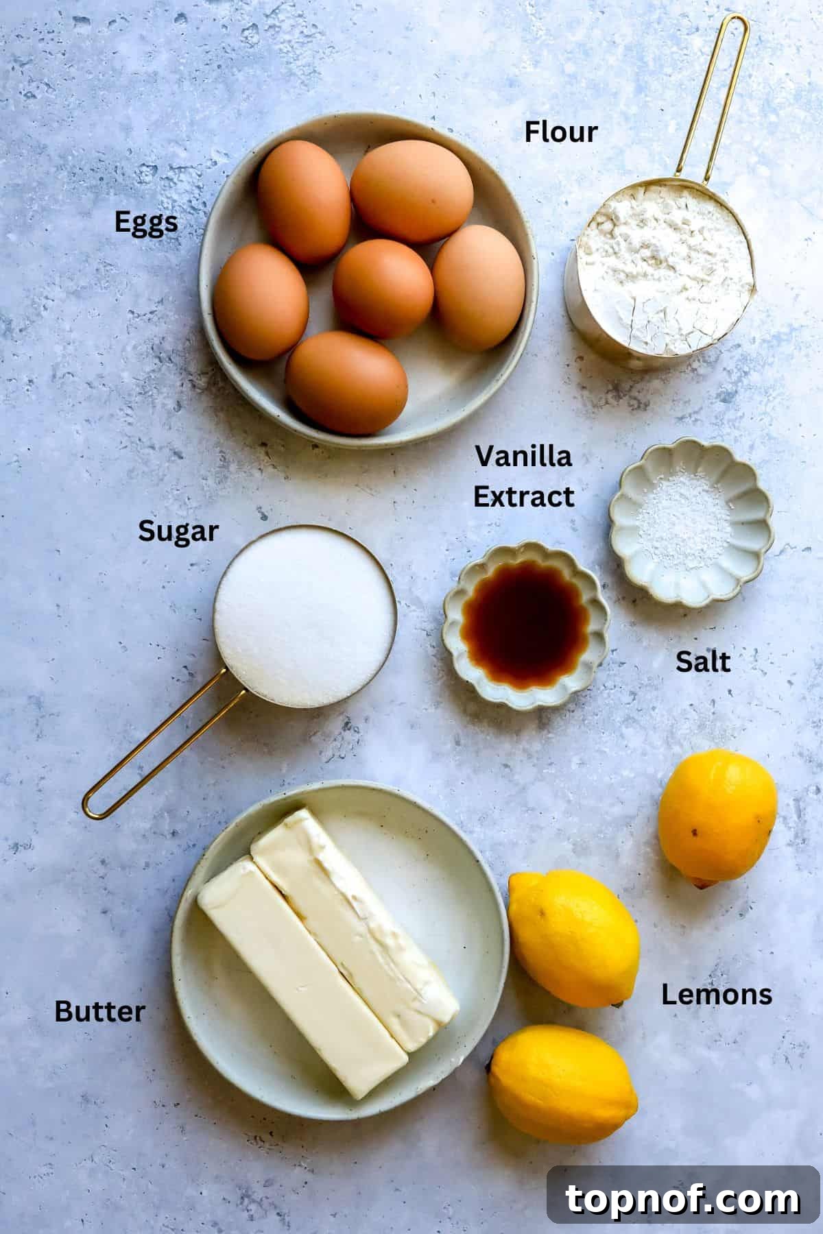 Key ingredients for Lemon Cookie Bars laid out on a clean countertop, including fresh lemons, butter, eggs, and flour.