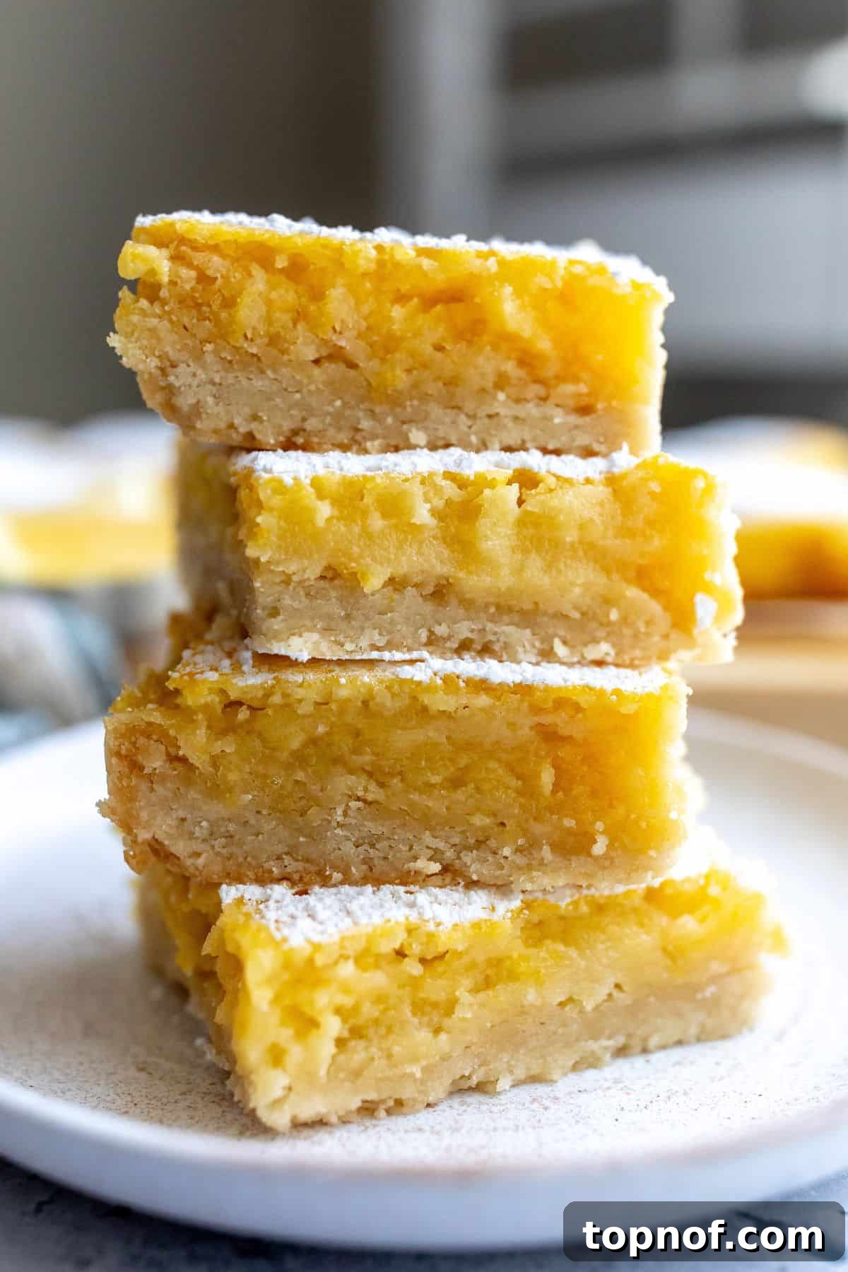 Perfectly cut Lemon Cookie Bars stacked on a white plate, ready to be served.