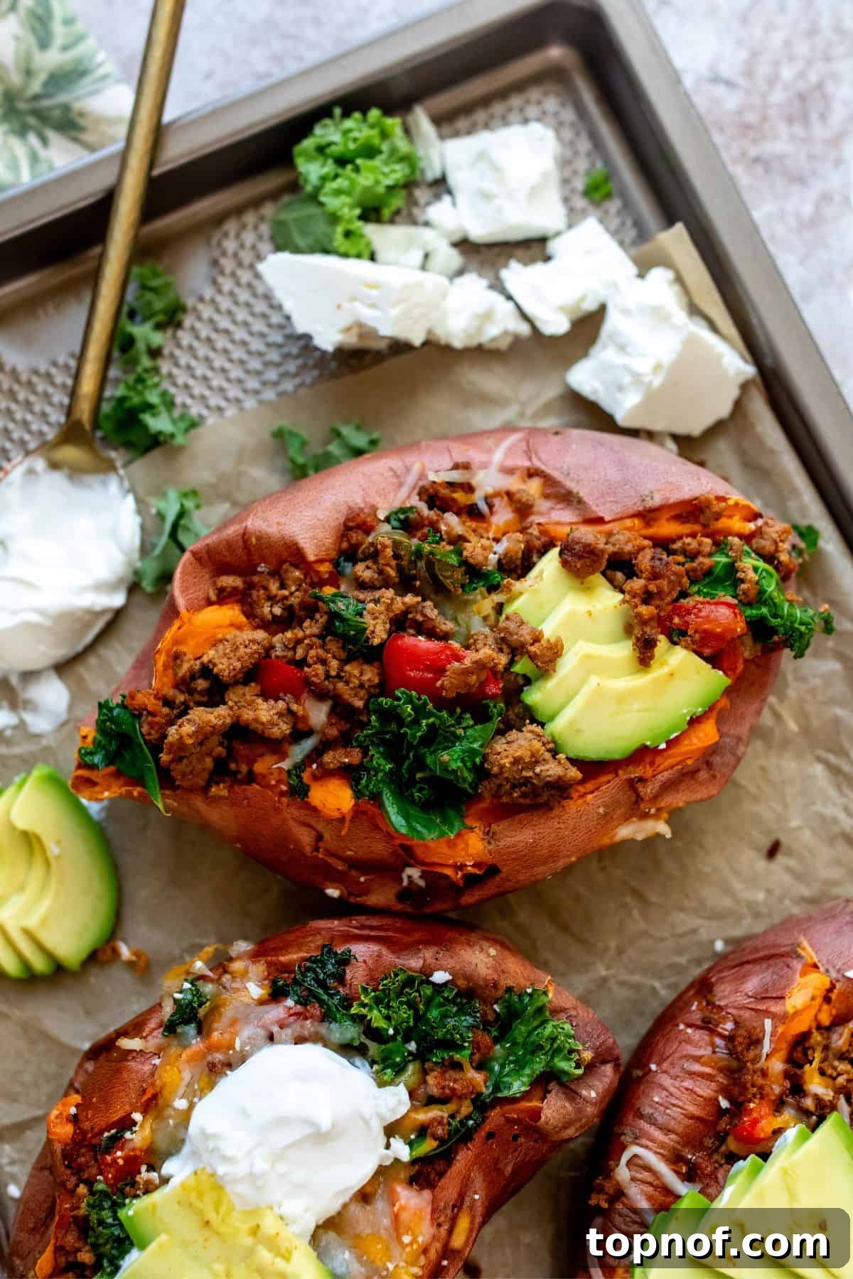 Savory Beef Sweet Potato Boats 2 Baking sheet with parchment paper and sweet potatoes loaded in toppings, ready to be served.