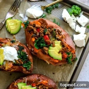 Baking sheet with parchment paper and sweet potatoes loaded in toppings.