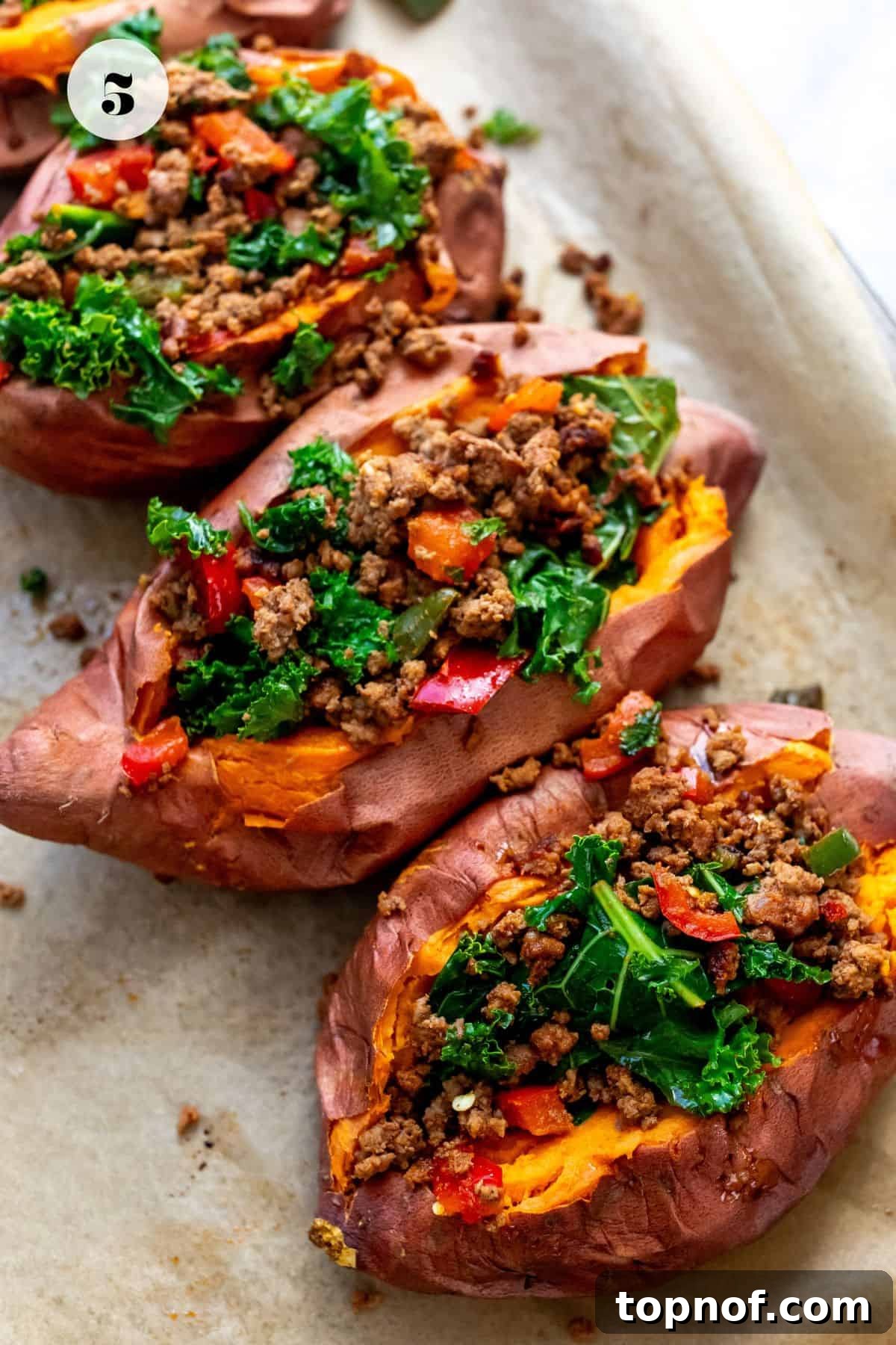 Savory Beef Sweet Potato Boats 5 Close up photo of sweet potatoes on a baking sheet stuffed with ground beef, ready for the oven.