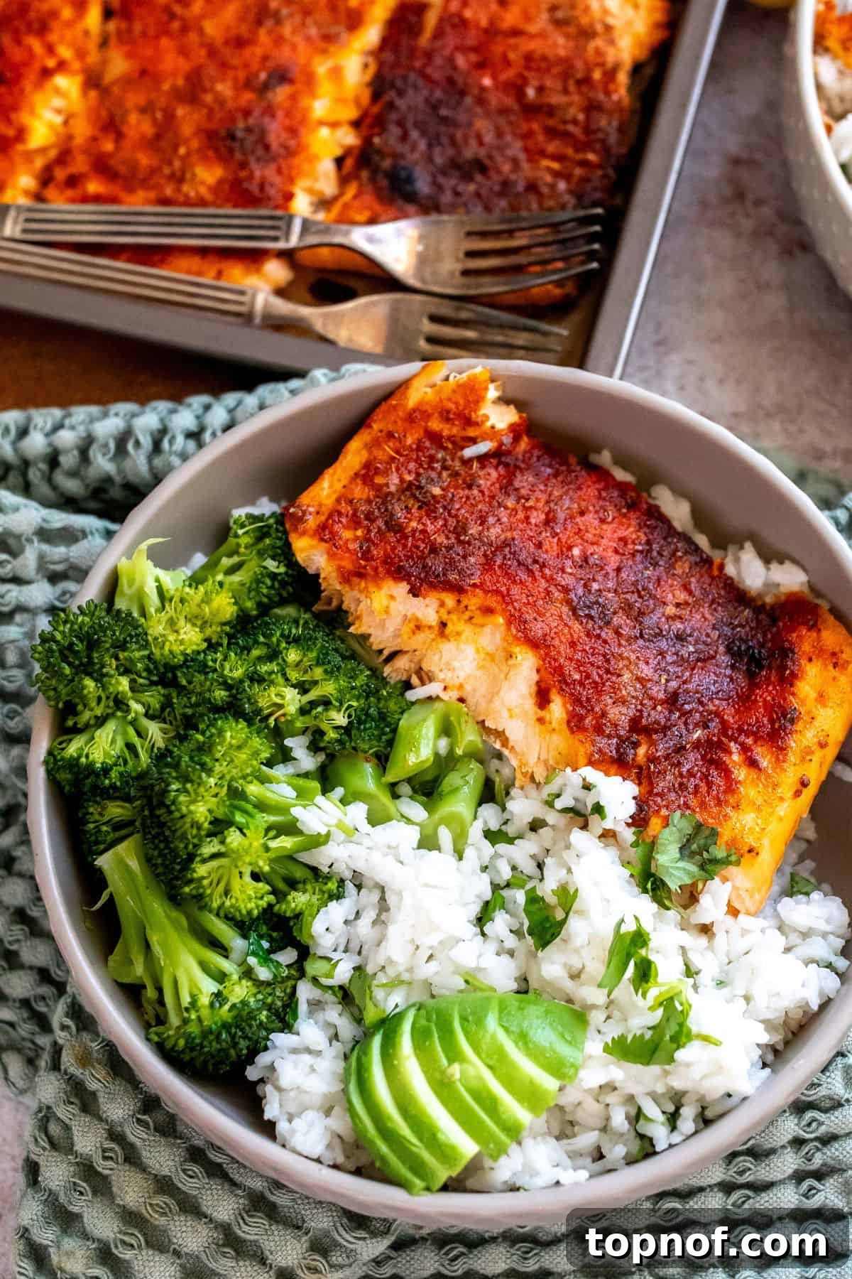 Zesty Baked Blackened Salmon 2 Grey bowl on a green towel with coconut rice and salmon in the bowl.