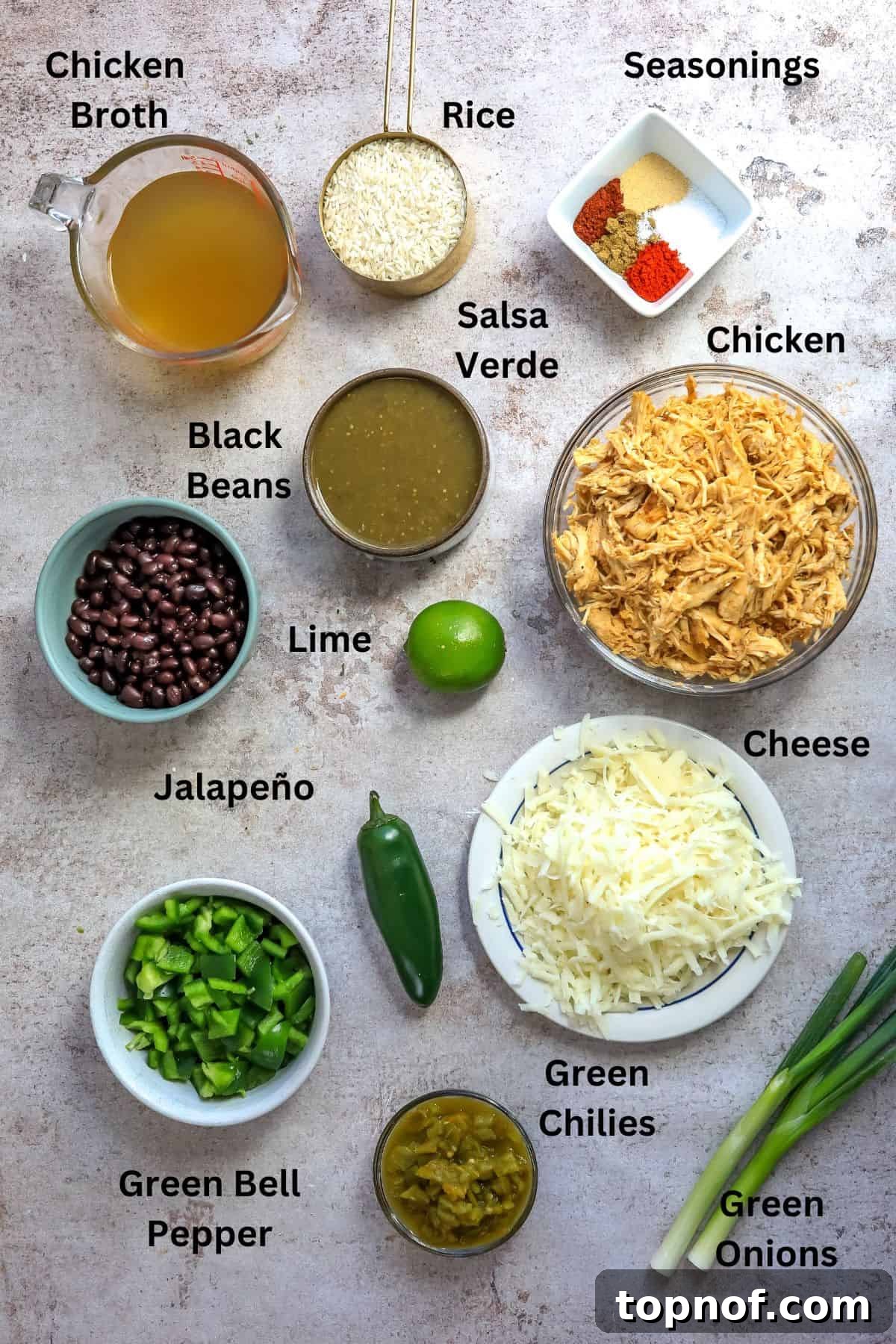 One-Pan Southwest Chicken Fiesta 3 An array of fresh ingredients laid out in bowls and measuring cups, including shredded chicken, rice, salsa verde, and various spices, ready for cooking.