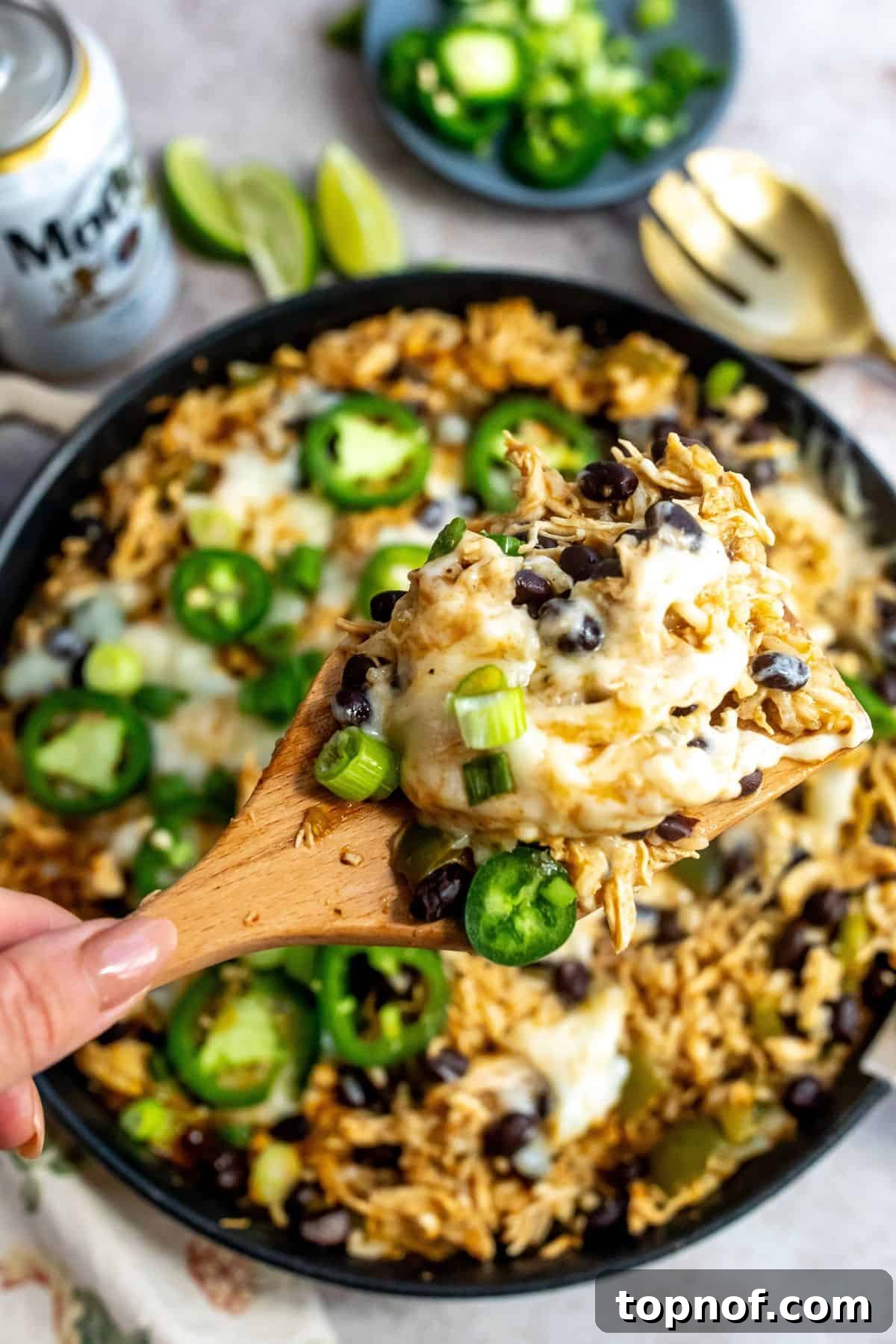 One-Pan Southwest Chicken Fiesta 5 A serving spoon lifting a generous portion of the Southwest Chicken Skillet, revealing the layers of chicken, rice, cheese, and salsa verde, ready to be plated.