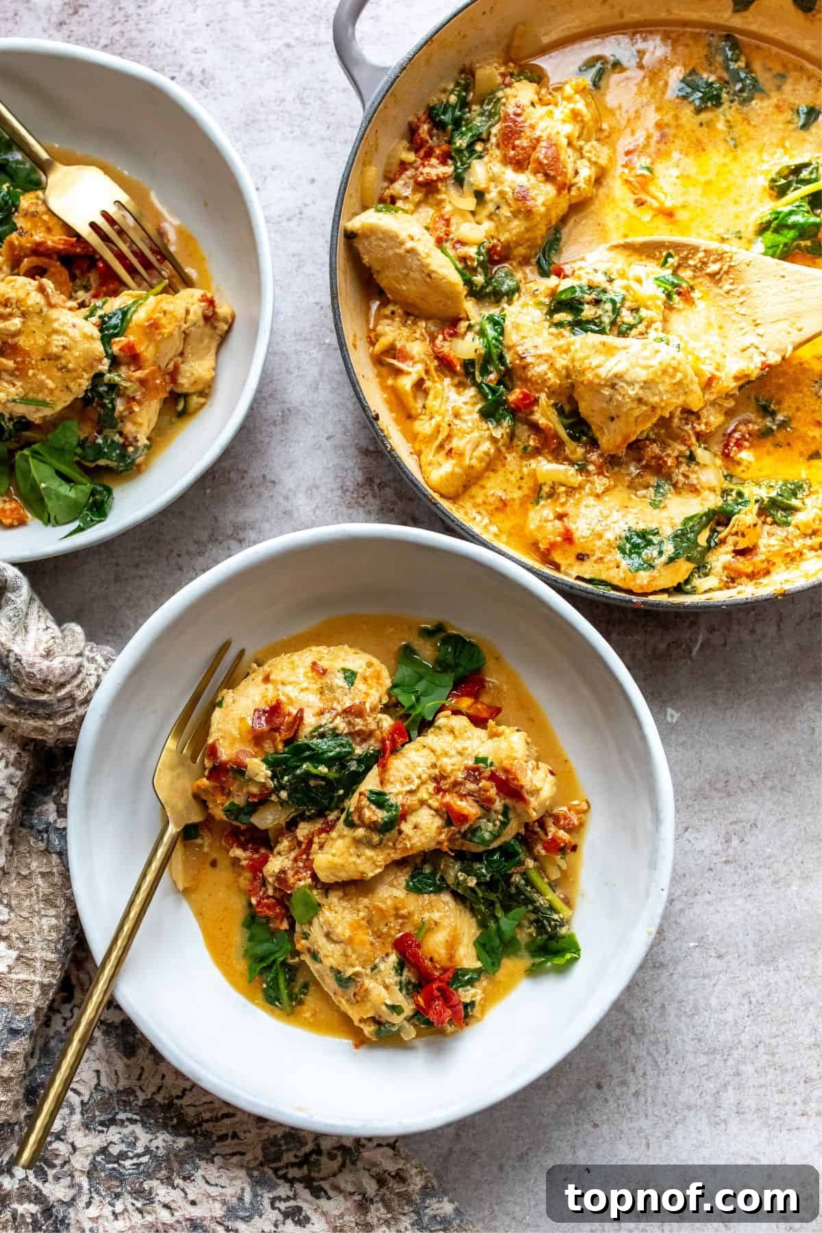 Creamy Tuscan Chicken Skillet 2 A white bowl showcasing creamy Tuscan chicken with a golden fork. Fresh bread slices are served on the side.