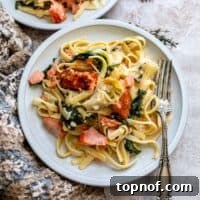 Lemon Herb Salmon Pasta Bake 6 White ceramic plate with pasta, cream sauce and salmon. A silver fork on the side.
