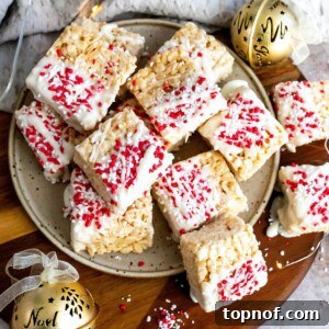 A festive plate of Christmas Rice Krispies treats, brightly adorned with holiday sprinkles and surrounded by soft, twinkling lights, ready to be enjoyed.