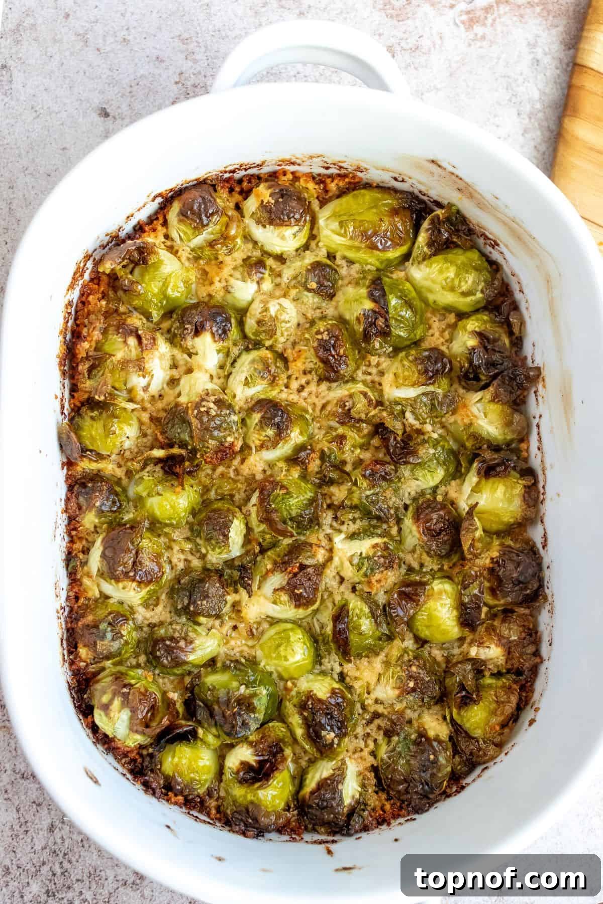 Crispy Parmesan Brussels Sprouts 5 White baking dish filled with perfectly golden and crispy Parmesan Crusted Brussels Sprouts, garnished with fresh herbs.