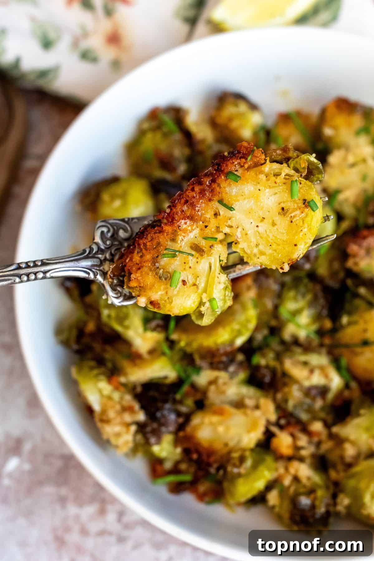 Crispy Parmesan Brussels Sprouts 6 Close-up of a single Parmesan Crusted Brussels Sprout on a silver fork, highlighting the crispy crust and golden color.