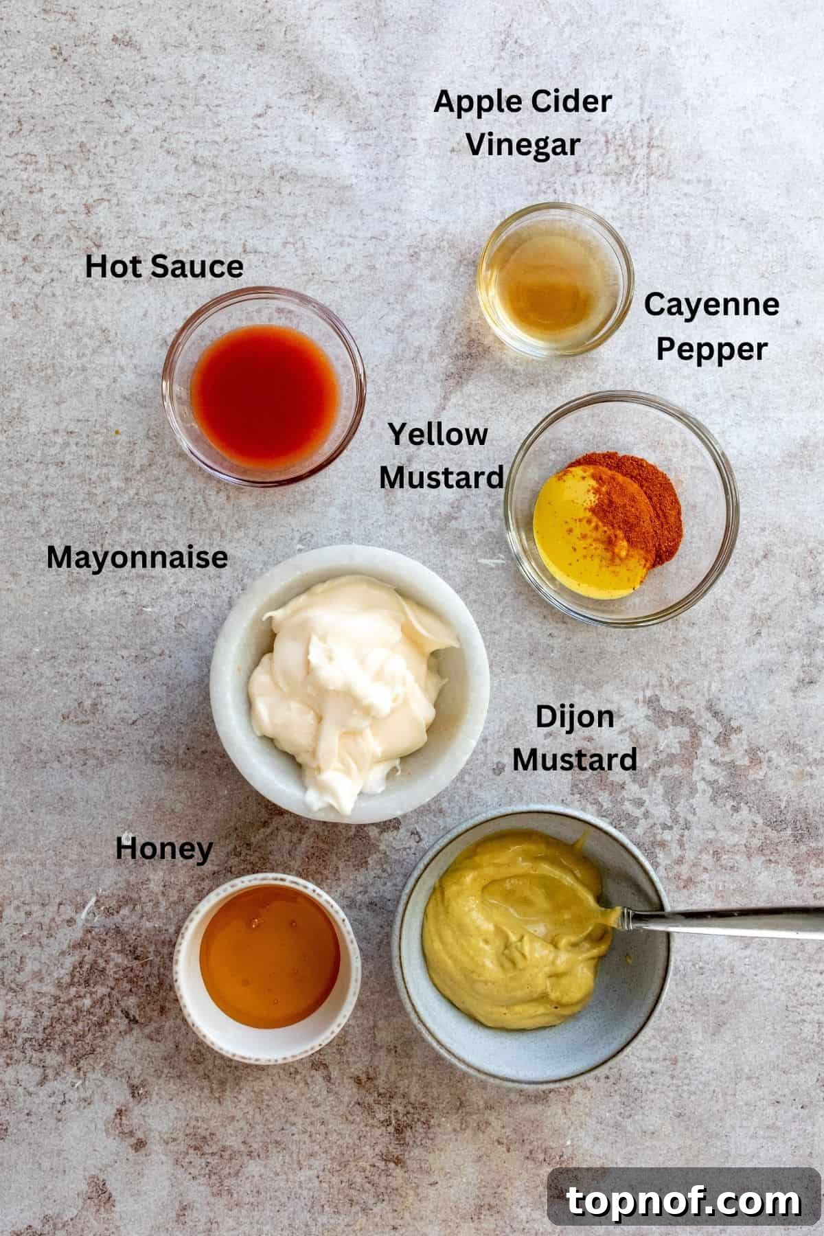 Hot Honey Mustard Sauce 3 A collection of small glass bowls containing the key ingredients for spicy honey mustard: Dijon mustard, hot sauce, mayonnaise, honey, and apple cider vinegar.