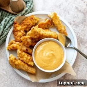 Spicy mustard with honey and seasonings in a bowl with chicken on the side.