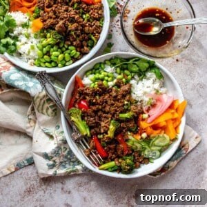 White Ceramic bowls with ground beef and teriyaki sauce. Fresh chopped veggies and a silver fork on the side.