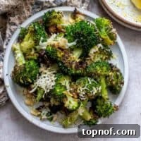 White bowl with charred broccoli and toppings mixed in.