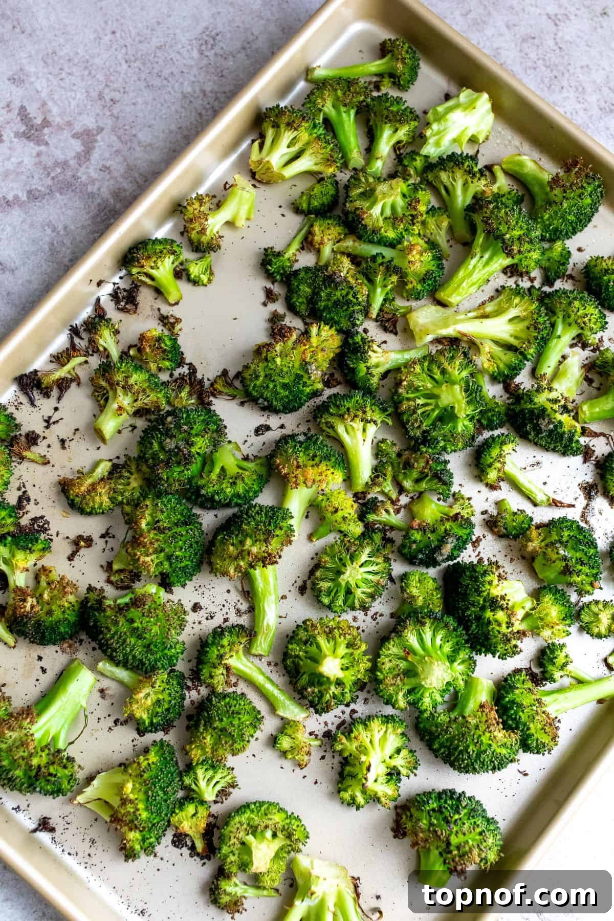 Close-up of perfectly charred broccoli florets spread out on a baking sheet, fresh from the oven.