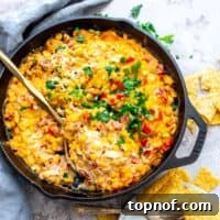 Black cast iron with corn and cream cheese mixed and topped with cilantro. Gold serving spoon in the mix to serve.