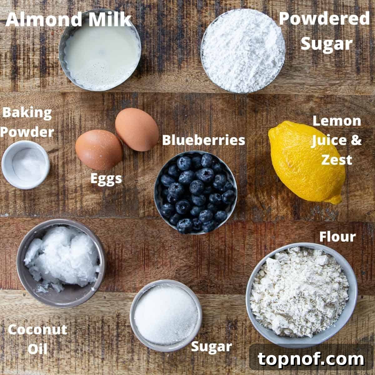 Here's what you need to make Easy Lemon Blueberry Breakfast Bread! Bowls of ingredients for Lemon Blueberry Bread including flour, sugar, eggs, oil, lemons, and blueberries laid out on a table.
