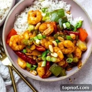 Pink ceramic bowls with rice and shrimp with sauce and peppers on it. Forks to the side.