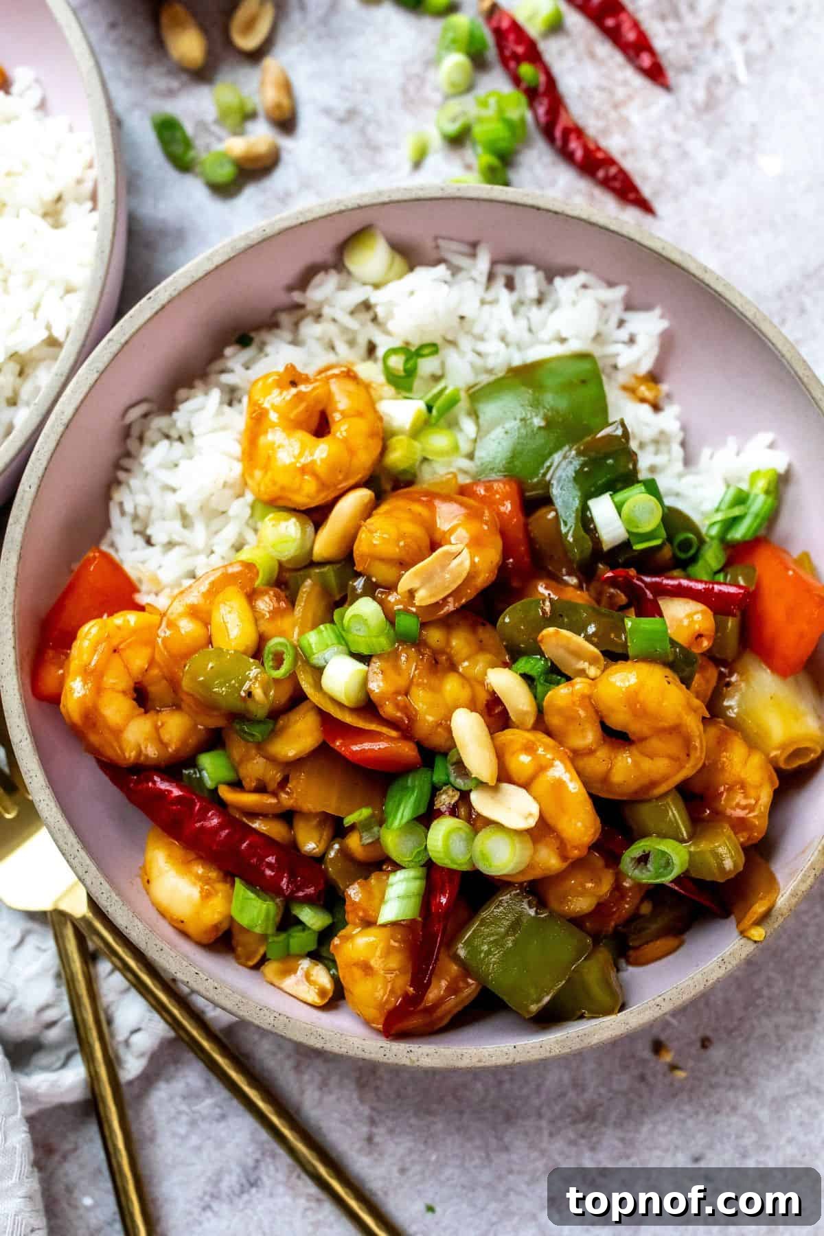Spicy Szechuan Kung Pao Shrimp 6 Pink ceramic bowls with rice and shrimp with sauce and peppers on it. Forks to the side.