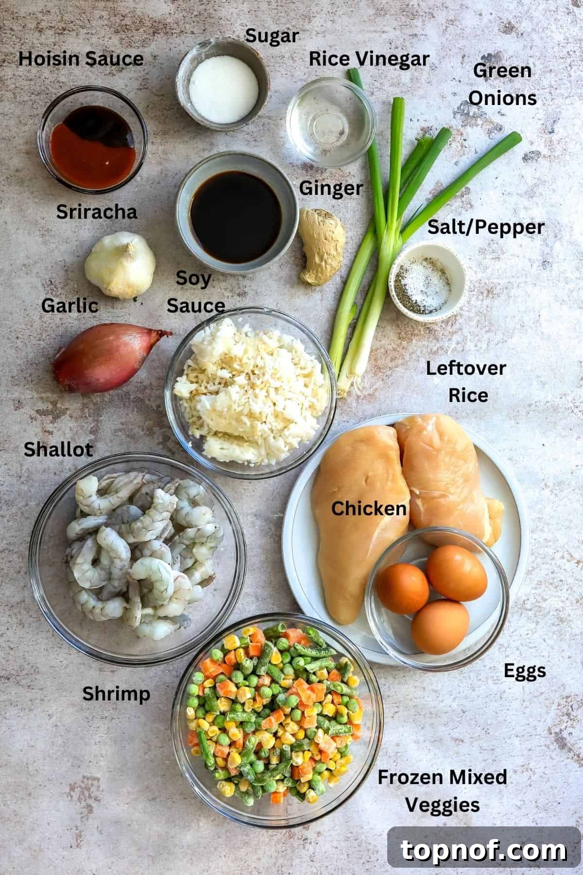 A selection of fresh ingredients laid out for making fried rice, including chicken, shrimp, vegetables, and sauces.