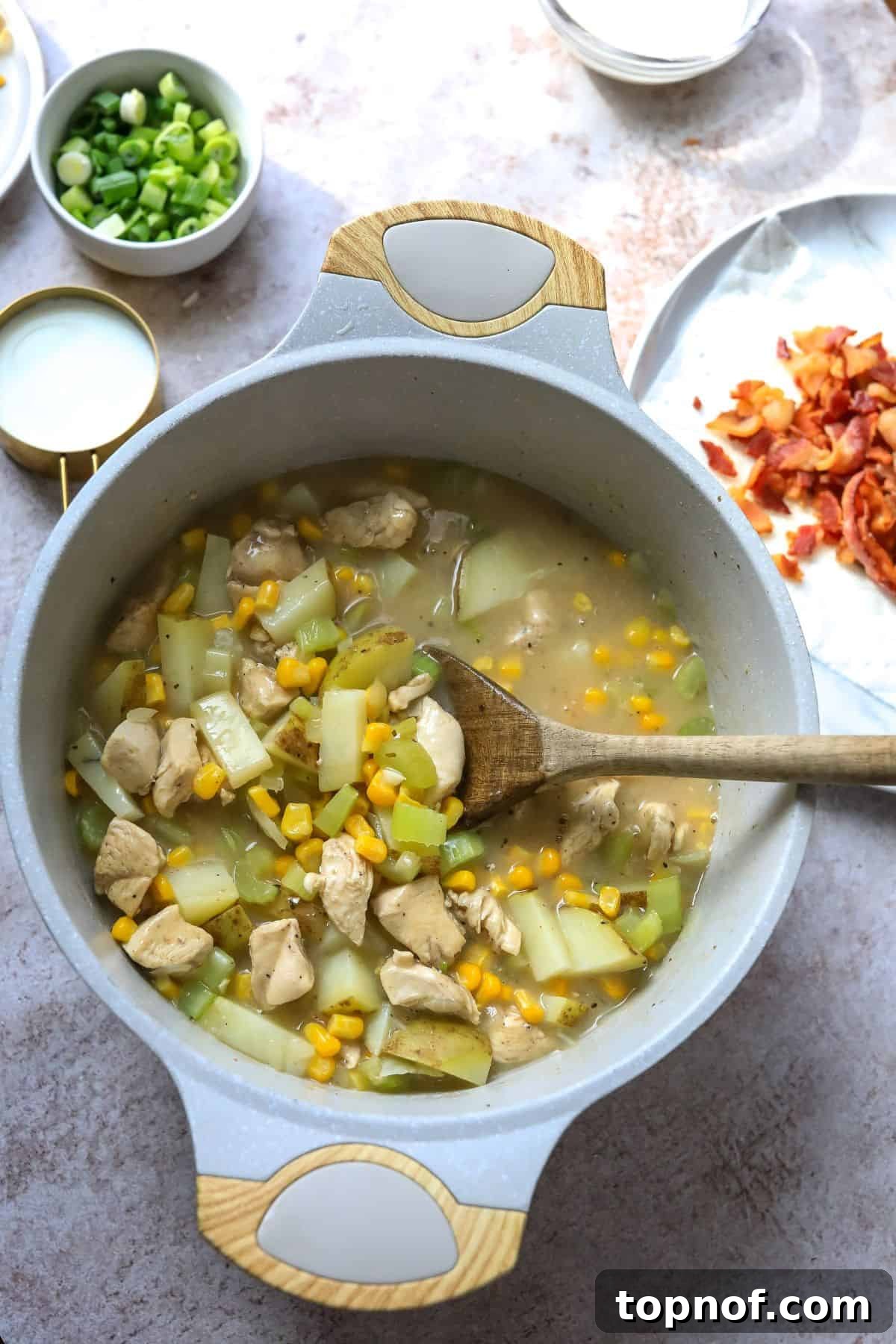 Golden Chicken Corn Chowder 5 Grey soup pot with chicken corn chowder and a wooden spoon.