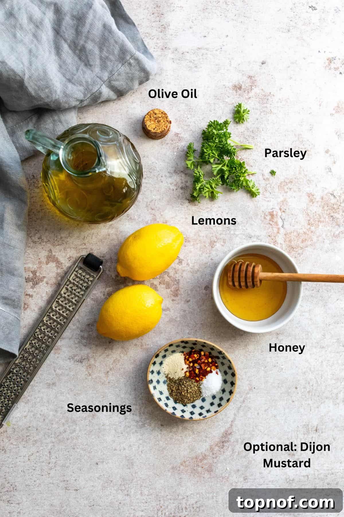 Bright Lemon Honey Dressing 3 All the essential ingredients for lemon honey dressing, including fresh lemons, a honey jar, olive oil, and various spices, displayed on a wooden surface.