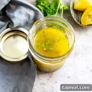Glass jar with lemon honey dressing in it. Olive oil on the side.