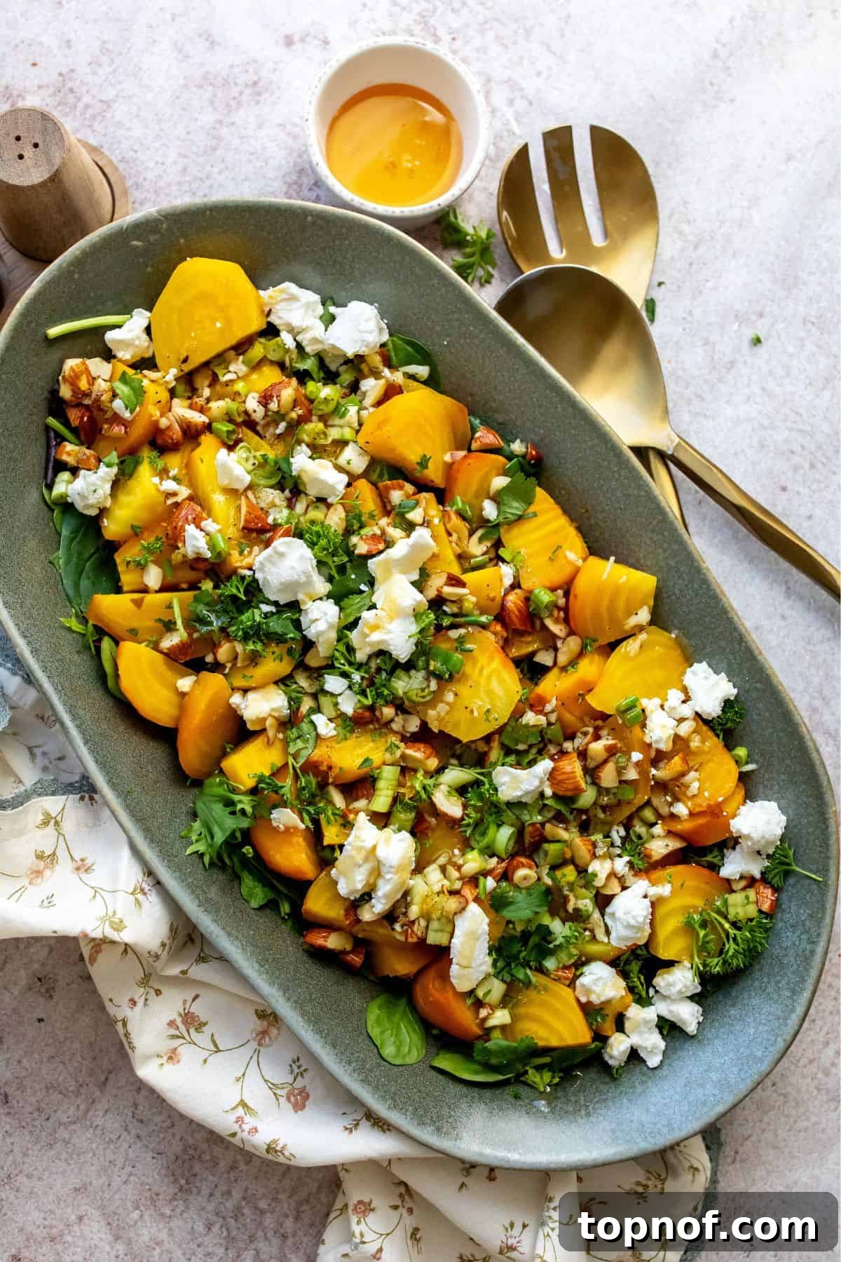 Golden Roasted Beets Perfection 2 Roasted Golden Beets on a green serving plate with toppings, garnished with fresh herbs.