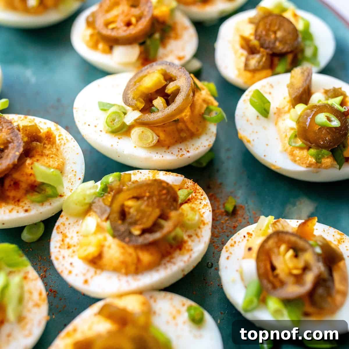 A green plate elegantly arranged with Spicy Deviled Eggs, garnished with various toppings, showcasing a modern twist on a classic.
