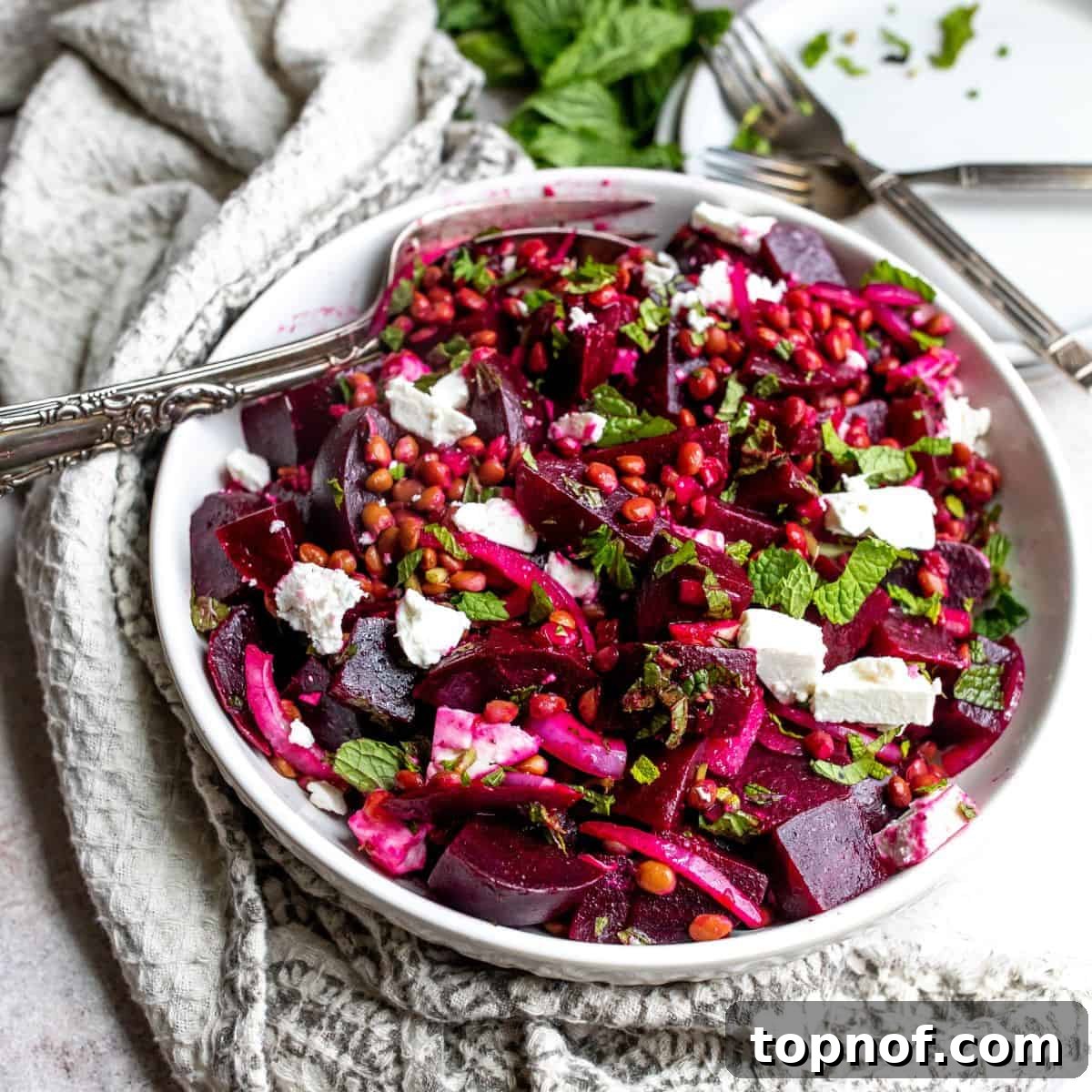 A white bowl featuring a vibrant Beetroot and Feta Salad with a fork, showcasing the beautiful colors and textures of beets and crumbled feta.