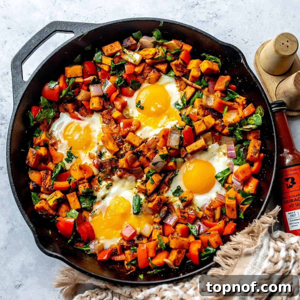 A rustic black skillet filled with savory Sweet Potato Hash and perfectly fried eggs on top, ready for breakfast or brunch.
