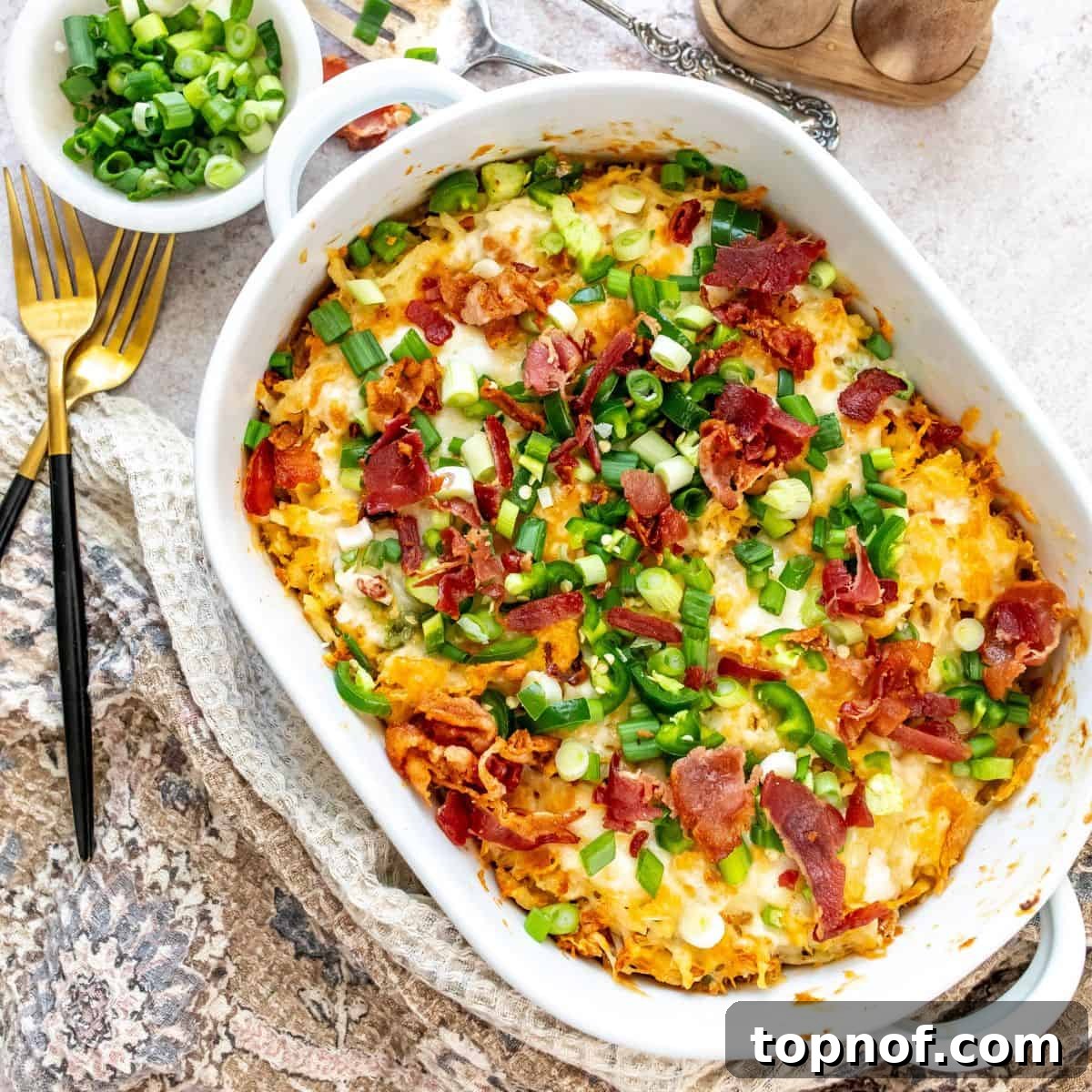 A white casserole dish filled with a hearty Jalapeño Popper Chicken And Hash Brown Casserole, featuring melted cheese and sliced jalapeños on top.