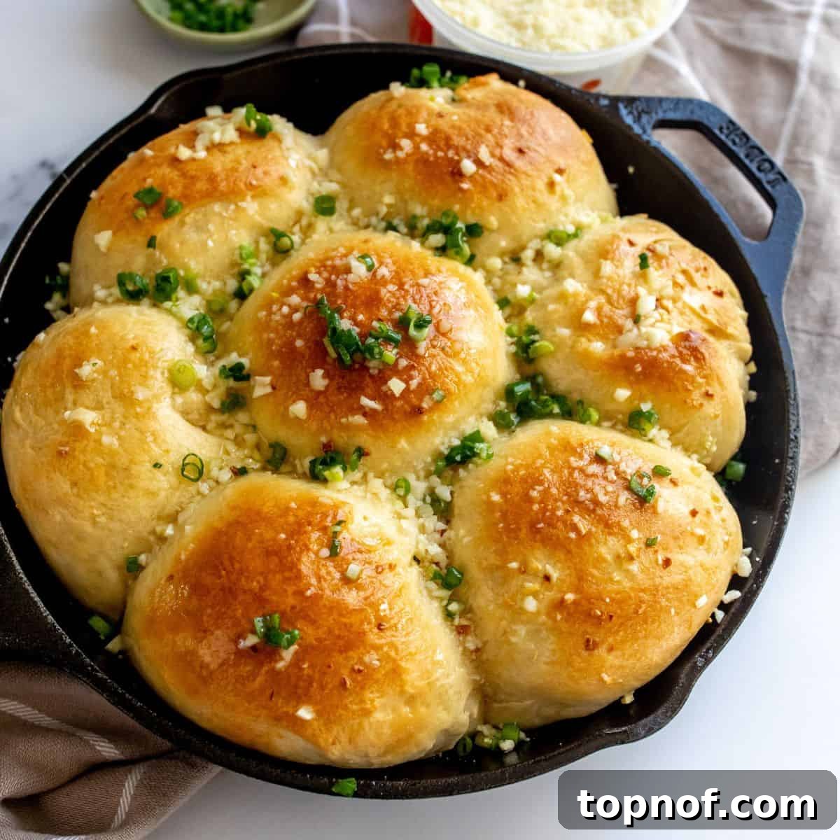 Warm, fluffy Garlic rolls in a cast iron pan with chives on top.