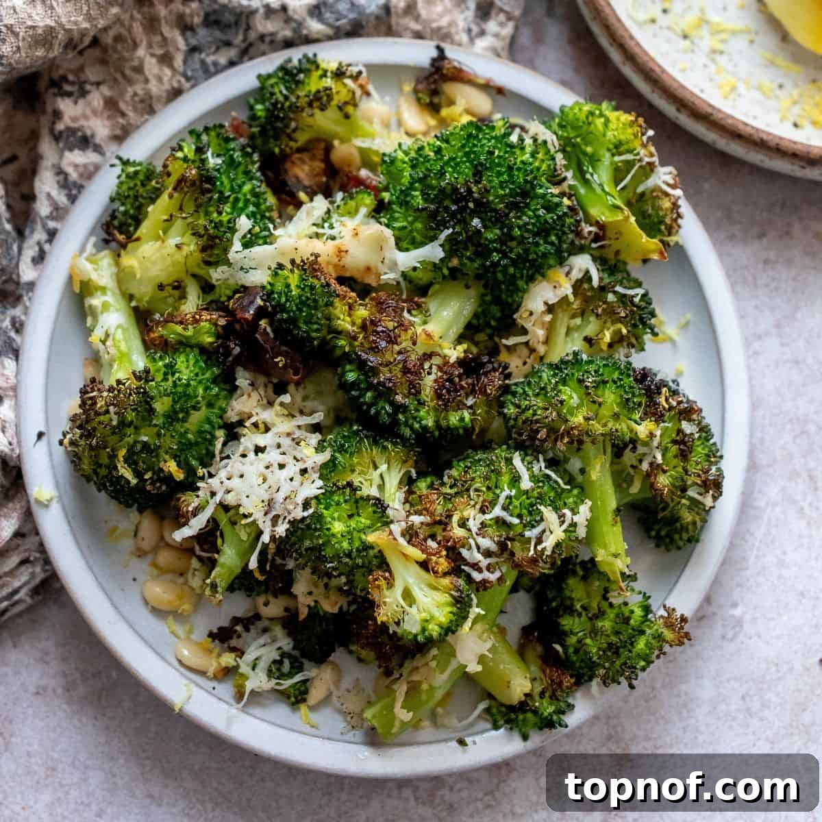 White bowl with perfectly charred broccoli and toppings mixed in.