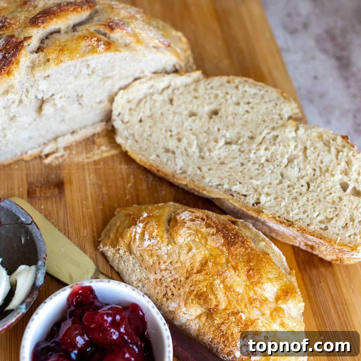 Freshly baked bread up close on a cutting board with jam to the side.