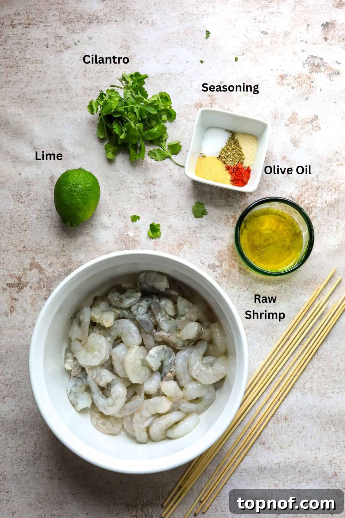 Oven-Kissed Shrimp Skewers 3 Small bowls containing the individual ingredients needed to make oven-baked shrimp skewers, including spices, olive oil, and lime, neatly arranged on a counter.