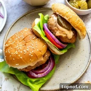 Air fryer spicy chicken burgers on a plate with a spoon of aioli to the side.