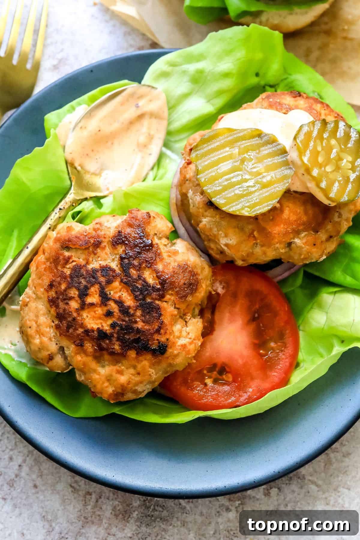 Blazing Chicken Burgers 6 Spicy Chicken Burgers presented in fresh lettuce wraps, topped with sliced pickles, offering a healthy and flavorful alternative to traditional buns.