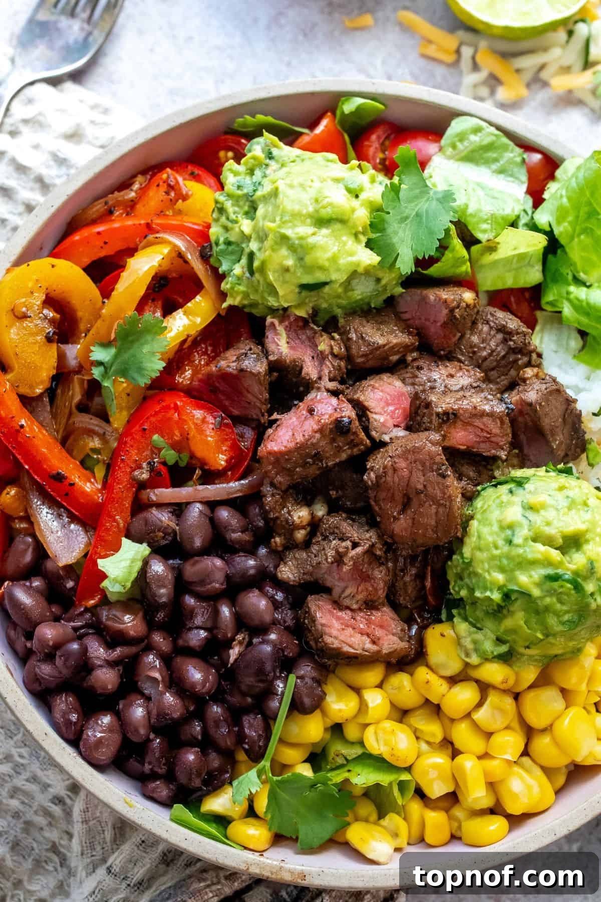 Hearty Steak and Rice Bowls 6 A beautifully assembled Chipotle Steak Bowl with tender steak, rice, and a colorful array of toppings, with a fork ready to scoop, showcasing a complete and inviting meal.