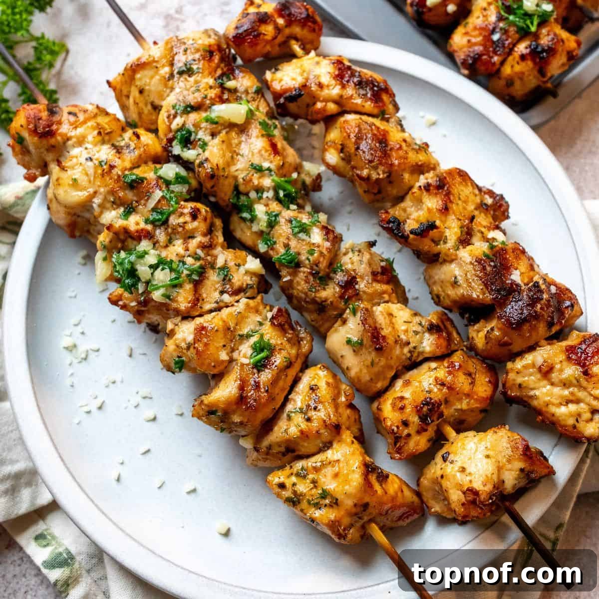 Juicy Garlic Parmesan Chicken Skewers beautifully arranged on a white plate.