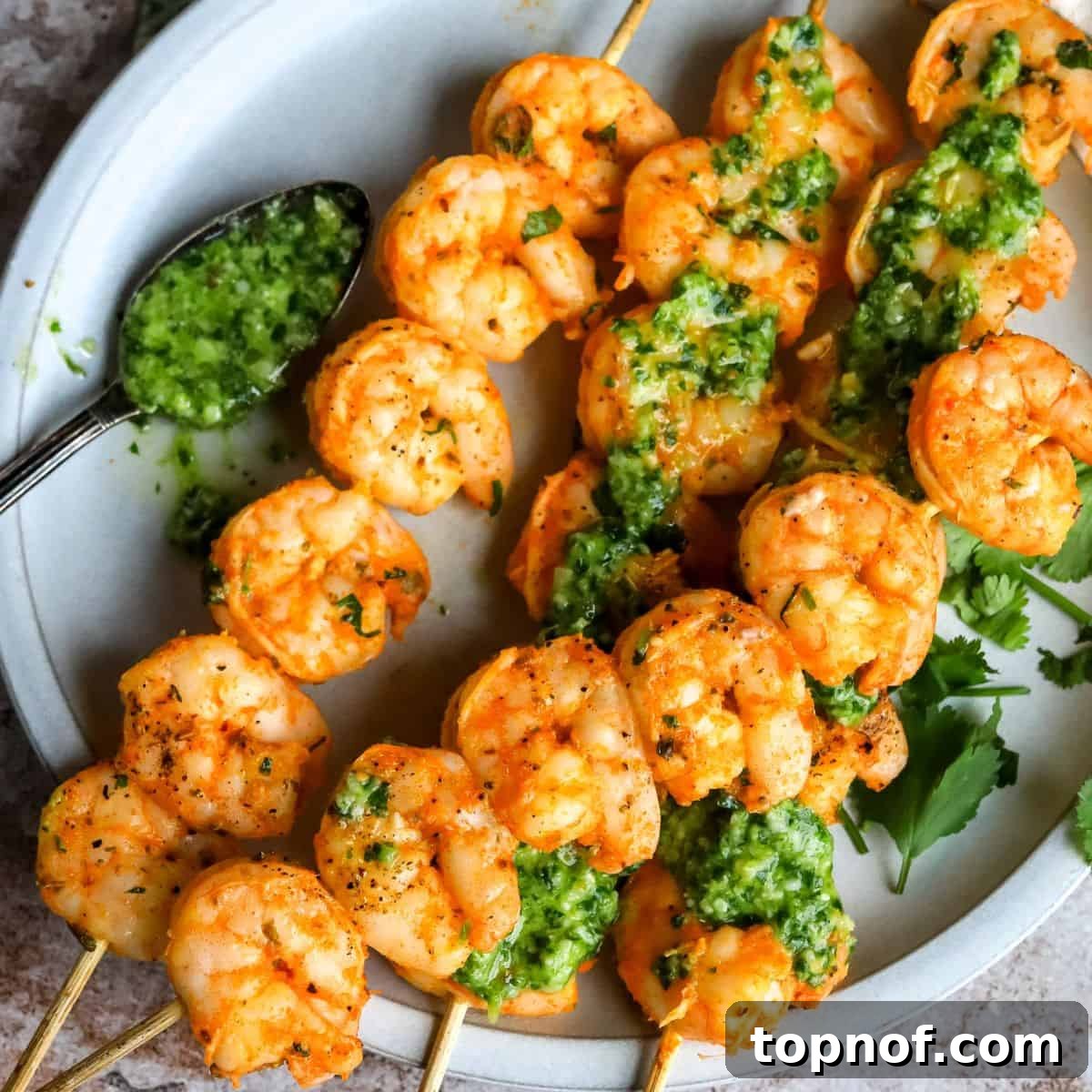 Perfectly cooked Oven Baked Shrimp Skewers, served on a white plate with a side of dipping sauce.
