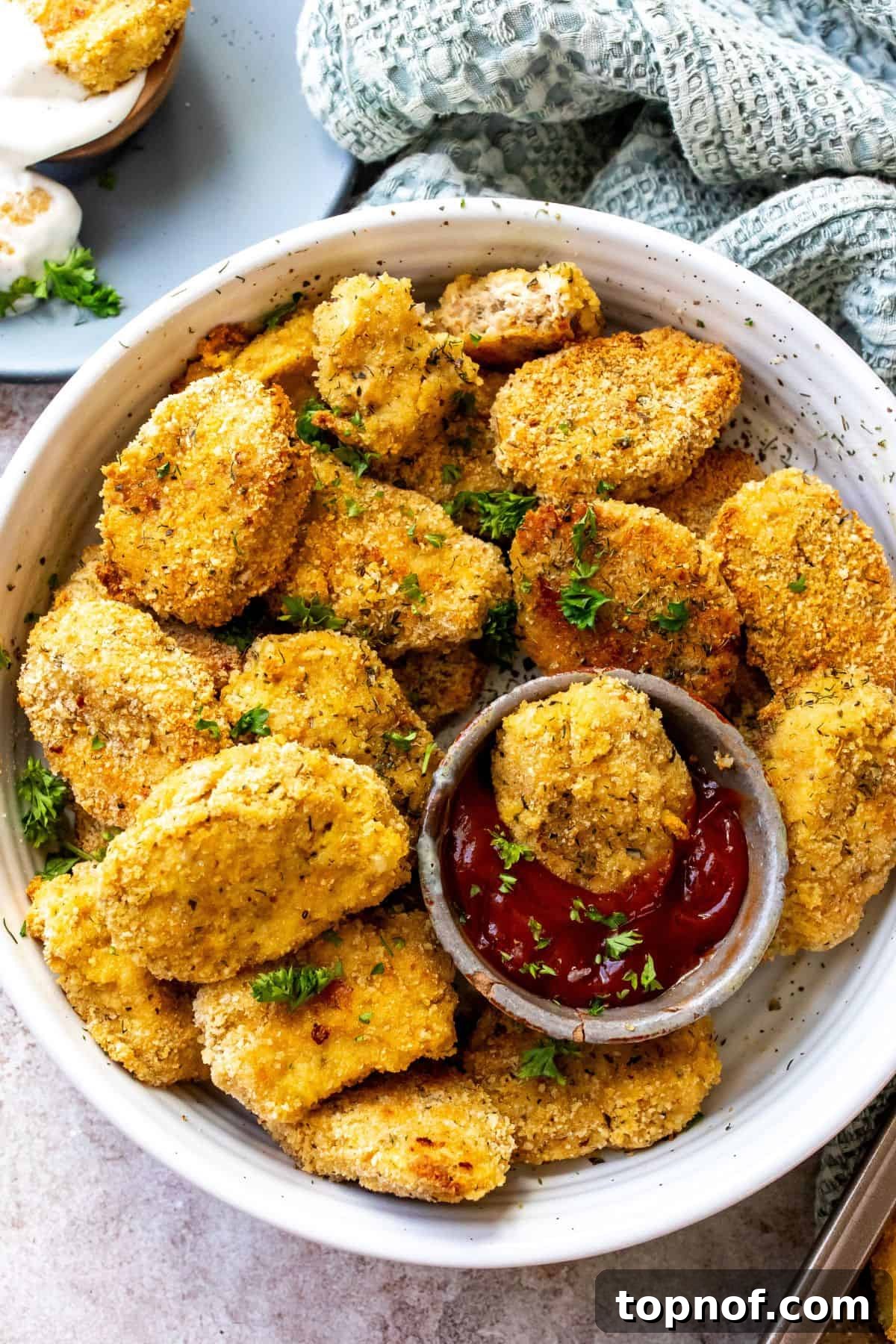 Delicious Ground Chicken Bites 2 White bowl with golden brown homemade ground chicken nuggets and a side of vibrant red ketchup.