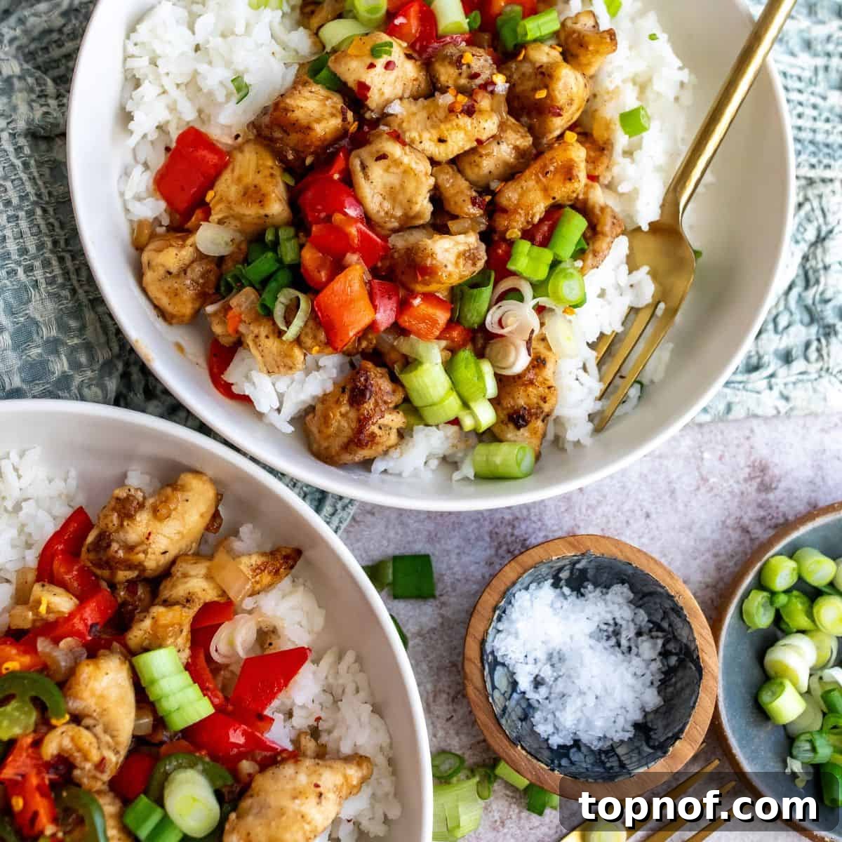 Crispy Salt and Pepper Chicken served over a bed of rice with accompanying vegetables.